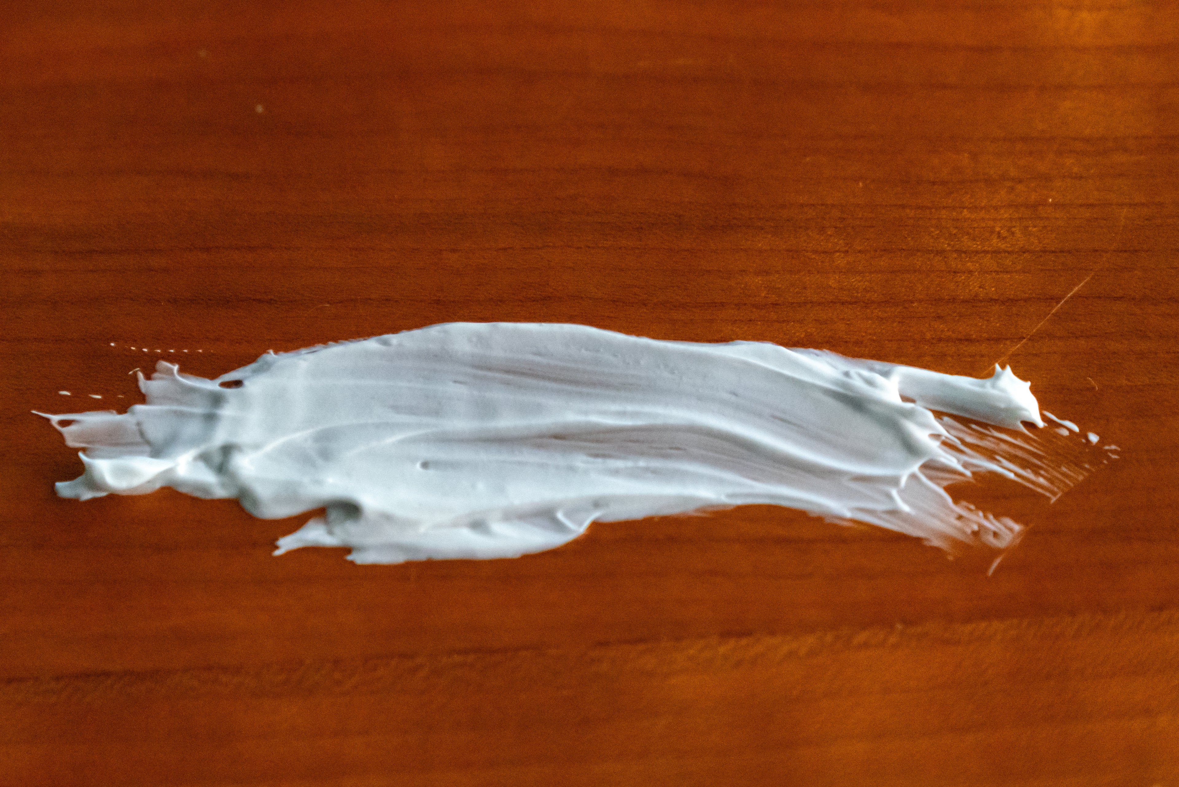 A picture of Naturallow's tallow moisturizer smeared across a woodgrain background