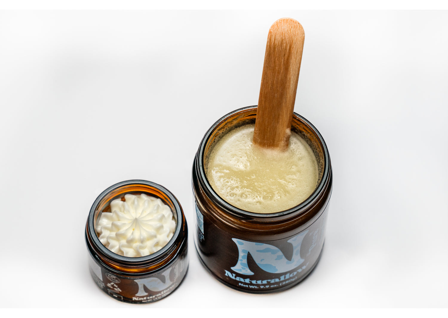 A top down photo showing off two jars. One of Naturallow's Whipped Moisturizer (left) and another Tallow Sugar Scrub (right) sitting side-by-side with the tops off of them